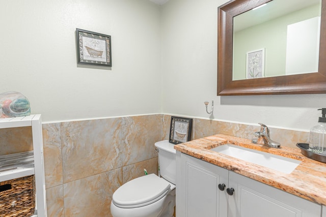 bathroom with vanity, tile walls, and toilet