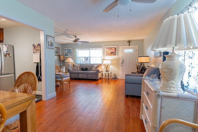 living room with dark wood-type flooring, ceiling fan, and a textured ceiling