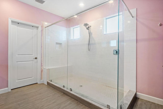 bathroom with wood-type flooring and a shower with shower door