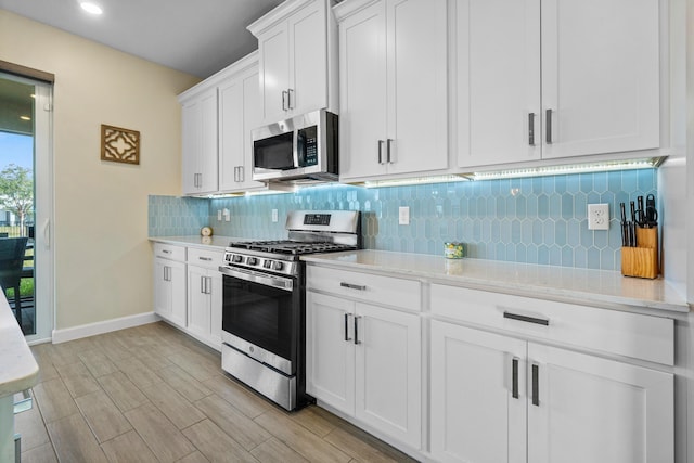 kitchen with white cabinetry, light stone counters, tasteful backsplash, and appliances with stainless steel finishes