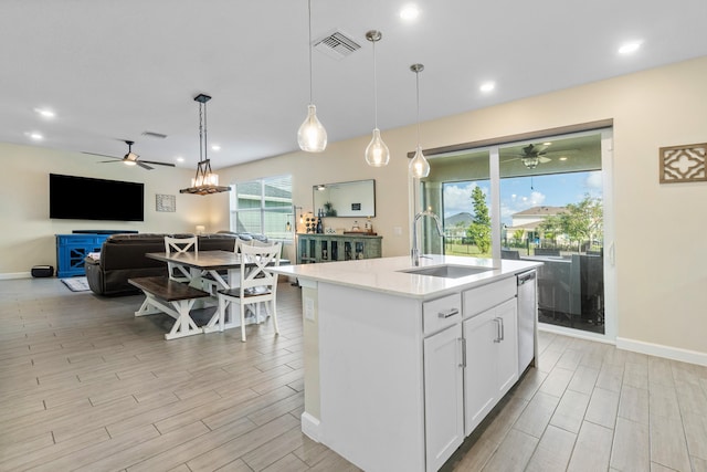 kitchen featuring pendant lighting, dishwasher, white cabinetry, sink, and a kitchen island with sink