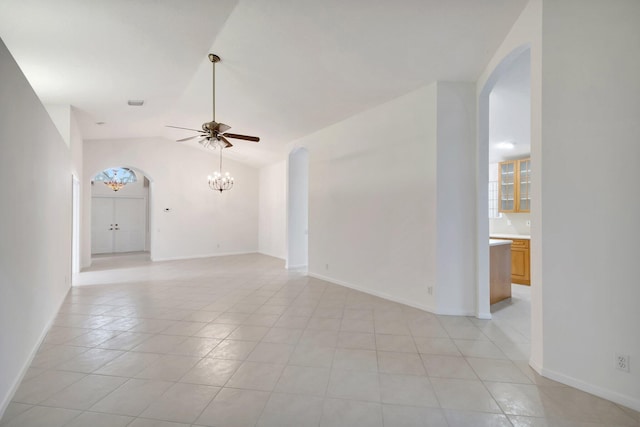 tiled empty room featuring ceiling fan with notable chandelier, vaulted ceiling, and plenty of natural light