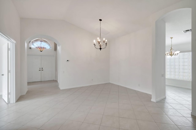 spare room featuring arched walkways, a notable chandelier, lofted ceiling, visible vents, and plenty of natural light