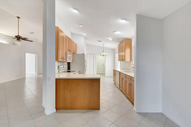 kitchen with white appliances, vaulted ceiling, light countertops, a sink, and ceiling fan with notable chandelier