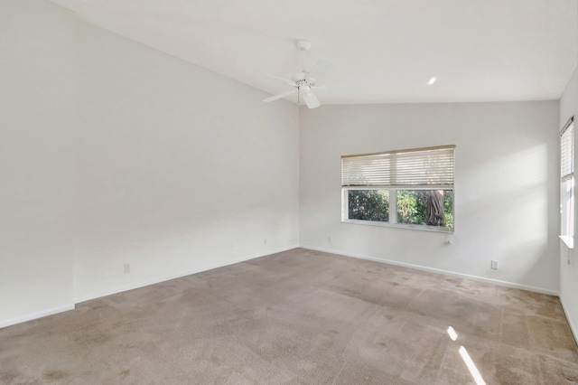 empty room featuring lofted ceiling, light carpet, and ceiling fan