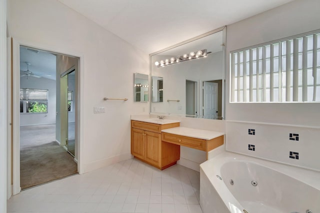 bathroom with a ceiling fan, vaulted ceiling, vanity, baseboards, and a tub with jets