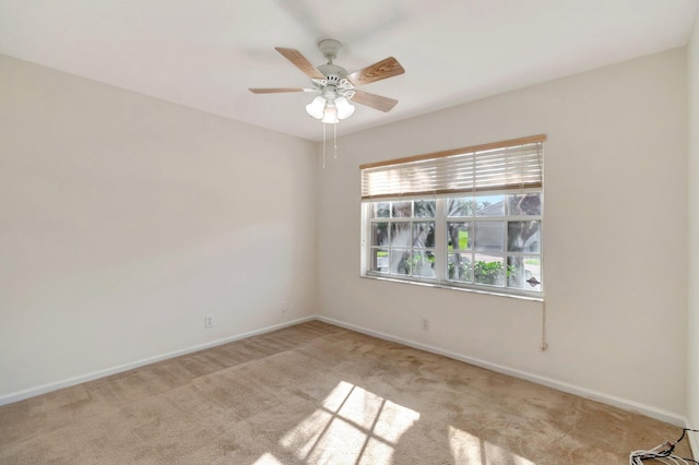 spare room featuring light carpet, ceiling fan, and baseboards