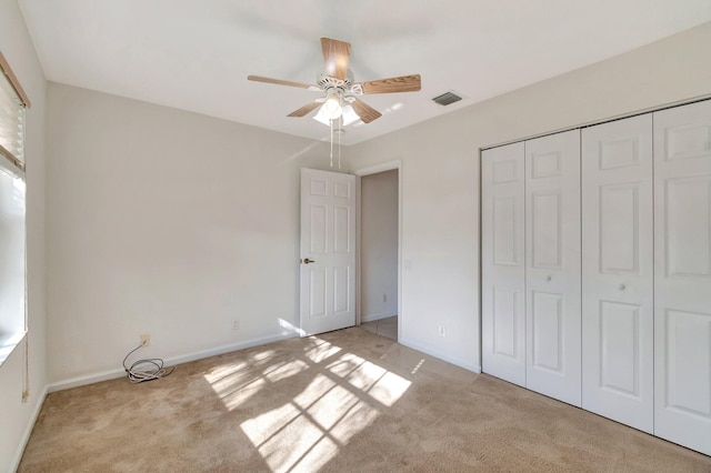 unfurnished bedroom featuring light carpet, baseboards, visible vents, and a closet