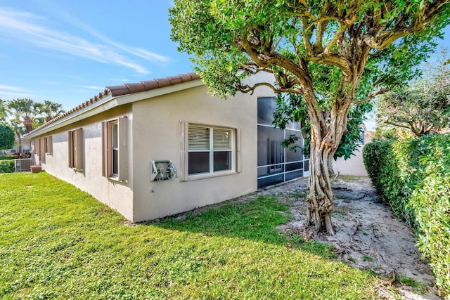 view of property exterior featuring cooling unit, a lawn, and stucco siding