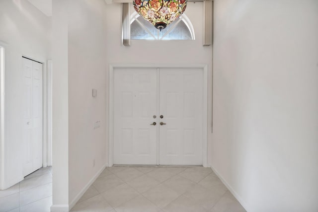 entrance foyer featuring light tile patterned flooring, a towering ceiling, and baseboards