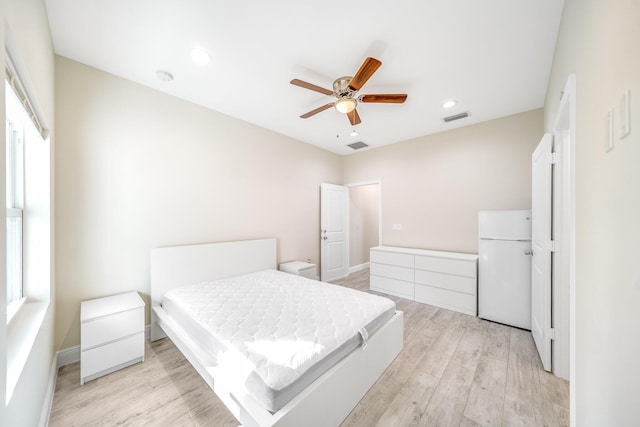 bedroom featuring ceiling fan, light hardwood / wood-style floors, and white fridge