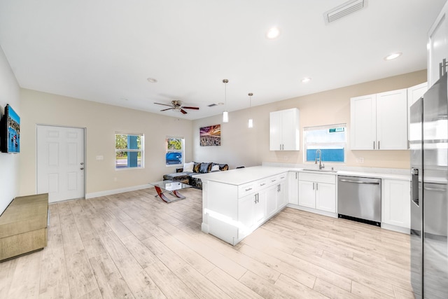 kitchen with stainless steel appliances, kitchen peninsula, hanging light fixtures, and white cabinets