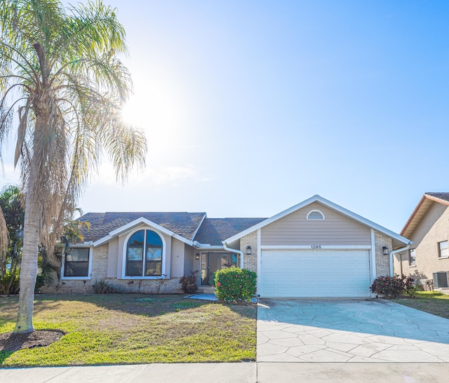 ranch-style home featuring a garage, cooling unit, and a front lawn