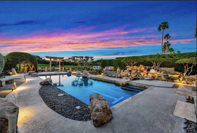 pool at dusk with a patio area