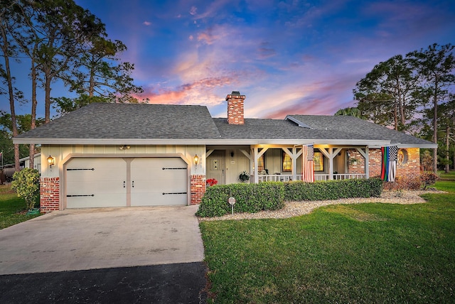 ranch-style house featuring a garage, a yard, and covered porch