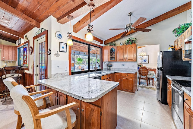 kitchen featuring sink, hanging light fixtures, stainless steel appliances, lofted ceiling with beams, and a kitchen bar