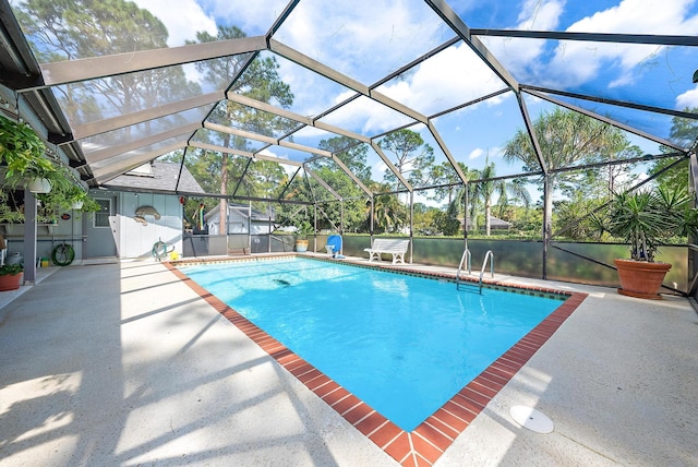 view of pool with a patio area, a water view, and glass enclosure