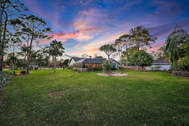 yard at dusk featuring a lanai