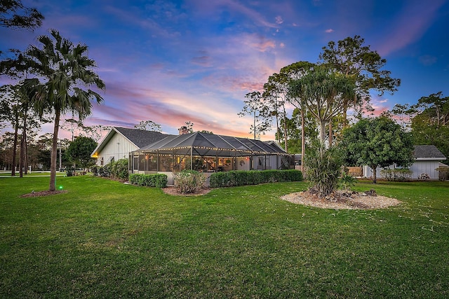 yard at dusk featuring a lanai