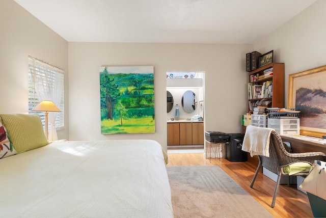 bedroom with connected bathroom and light hardwood / wood-style floors