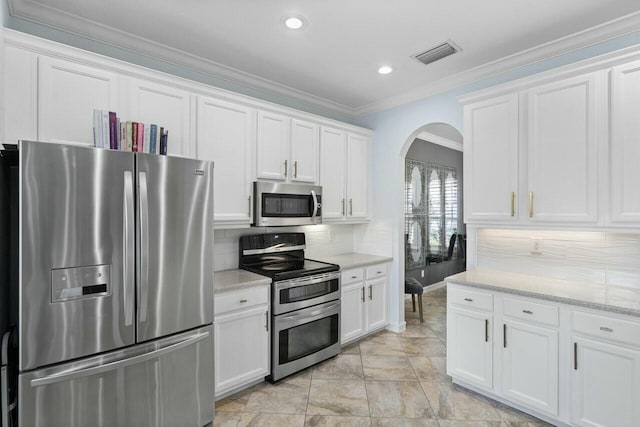 kitchen featuring visible vents, arched walkways, appliances with stainless steel finishes, white cabinetry, and backsplash