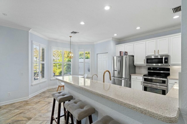 kitchen with visible vents, crown molding, baseboards, white cabinets, and stainless steel appliances