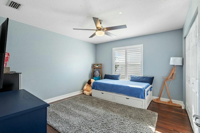 bedroom with ceiling fan, visible vents, baseboards, and dark wood-style floors