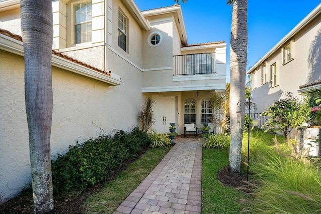 entrance to property with a balcony and stucco siding