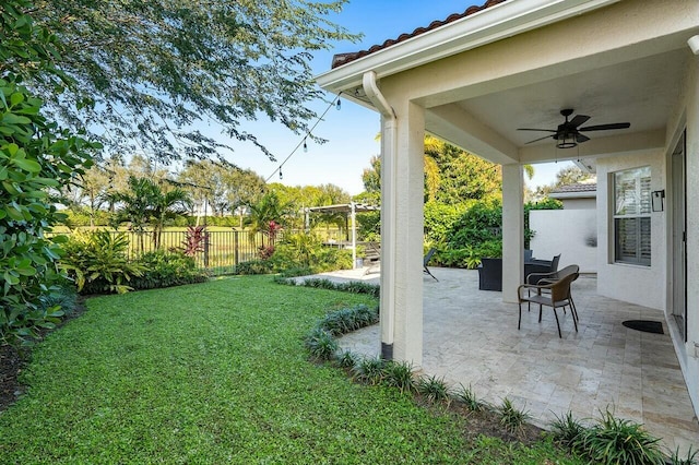 view of yard featuring a patio area, ceiling fan, and fence