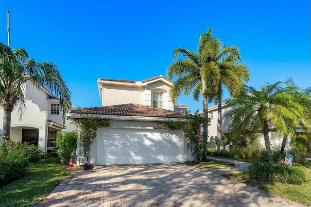 mediterranean / spanish house with stucco siding, a tile roof, decorative driveway, and a garage