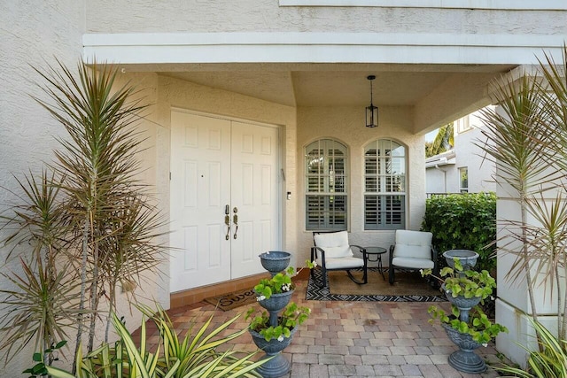 entrance to property featuring a porch and stucco siding