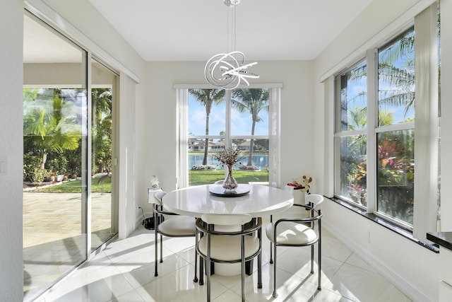 dining area with light tile patterned flooring, a water view, and a chandelier