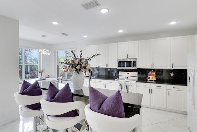 kitchen featuring pendant lighting, backsplash, white appliances, and white cabinetry