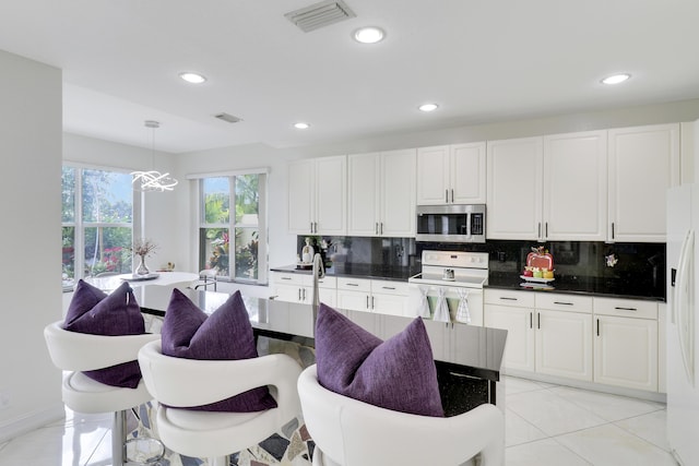 kitchen with light tile patterned flooring, tasteful backsplash, decorative light fixtures, white appliances, and white cabinets