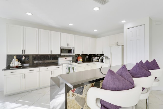 kitchen featuring backsplash, white cabinets, white appliances, and light tile patterned floors