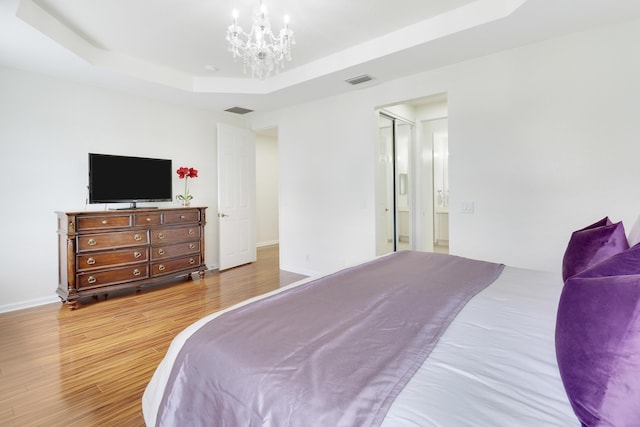 bedroom featuring a tray ceiling, a chandelier, and hardwood / wood-style floors