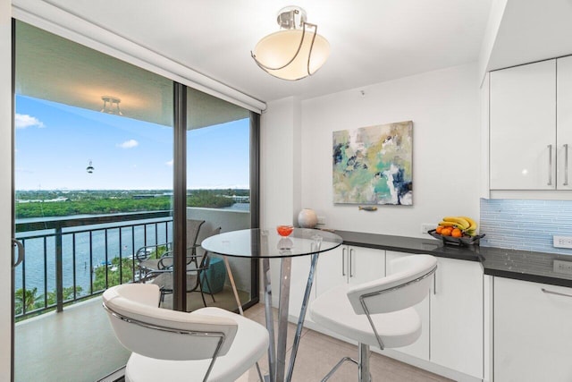 dining room featuring a water view and a wall of windows