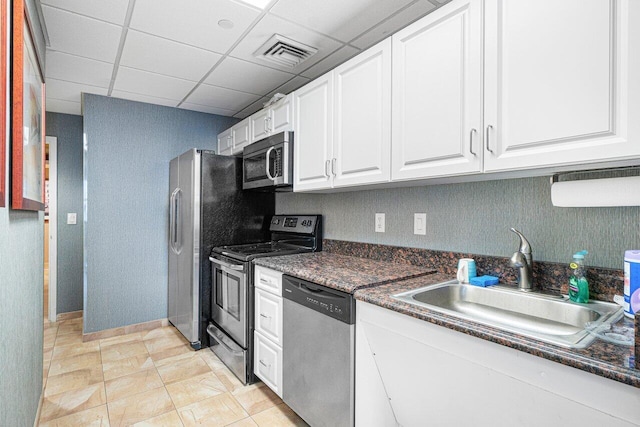 kitchen with stainless steel appliances, sink, a drop ceiling, and white cabinets