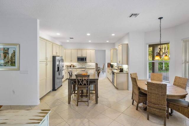 tiled dining area with an inviting chandelier, sink, and a textured ceiling