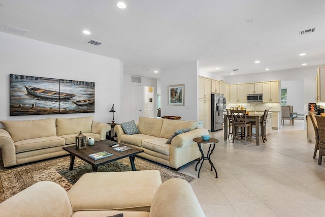 tiled living room featuring sink and a textured ceiling