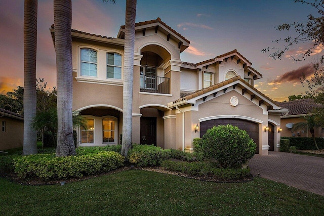 mediterranean / spanish house featuring a yard, a garage, and a balcony