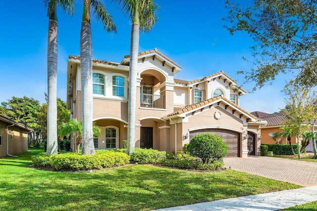 8187 Mariano Falls Ln, Boynton Beach, FL 33473 - mediterranean / spanish home featuring stucco siding, decorative driveway, a front yard, a balcony, and a garage