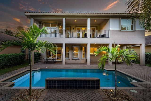 back house at dusk with a patio and a balcony