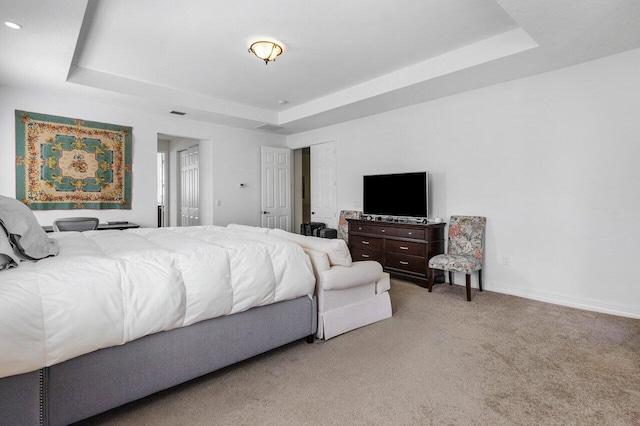 carpeted bedroom featuring a raised ceiling