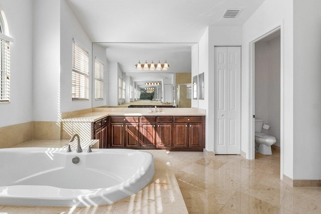 bathroom with vanity, a relaxing tiled tub, and toilet