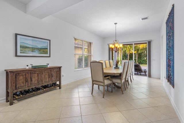 dining room with light tile patterned flooring, a notable chandelier, and a textured ceiling