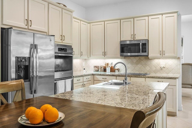 kitchen featuring light tile patterned flooring, stainless steel appliances, light stone countertops, and cream cabinetry