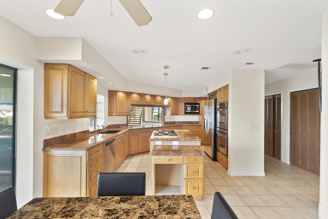 kitchen with sink, hanging light fixtures, appliances with stainless steel finishes, a kitchen island, and light stone countertops