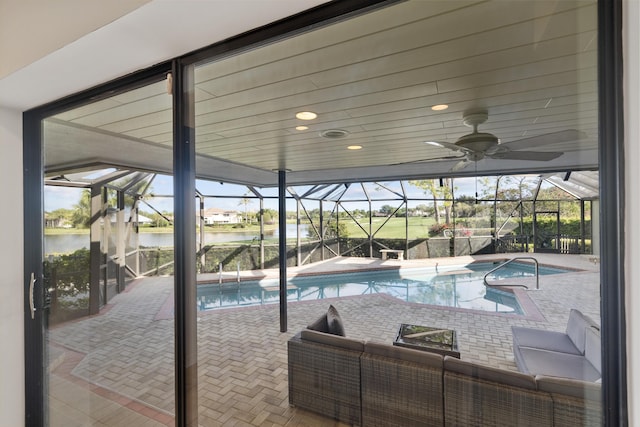 view of pool featuring a water view, a hot tub, a lanai, ceiling fan, and a patio