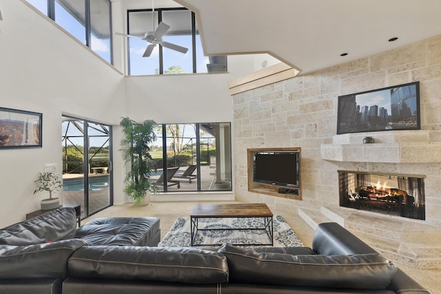 living room featuring ceiling fan, a multi sided fireplace, and a high ceiling